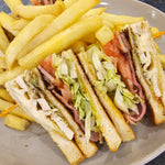 Book Club triple-decker sandwich with grilled chicken, bacon, avocado, tomato, cheese, lettuce, and mayo served with chips at The Social Cafe in Emerald QLD 4720.