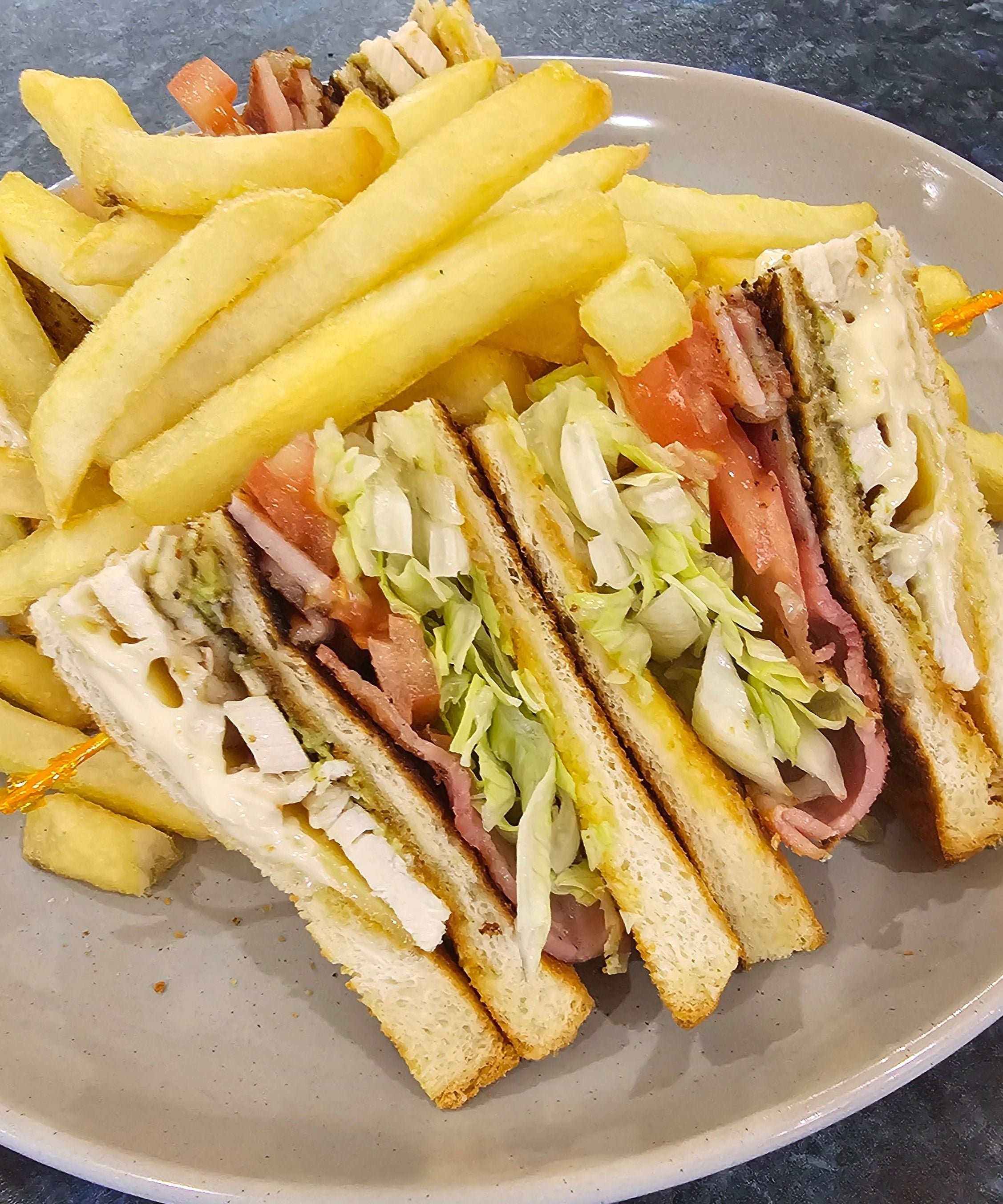 Book Club triple-decker sandwich with grilled chicken, bacon, avocado, tomato, cheese, lettuce, and mayo served with chips at The Social Cafe in Emerald QLD 4720.
