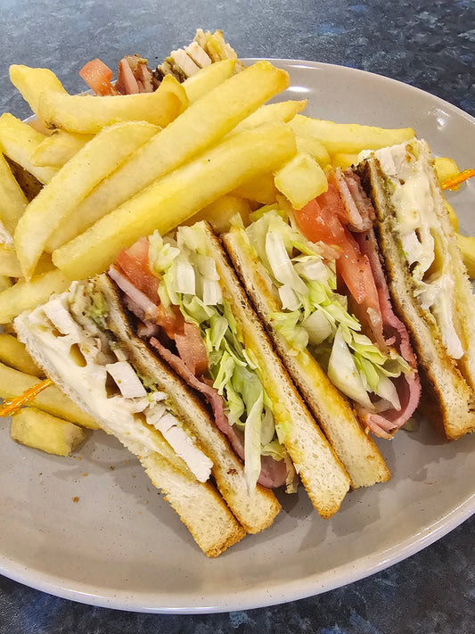 Book Club triple-decker sandwich with grilled chicken, bacon, avocado, tomato, cheese, lettuce, and mayo served with chips at The Social Cafe in Emerald QLD 4720.