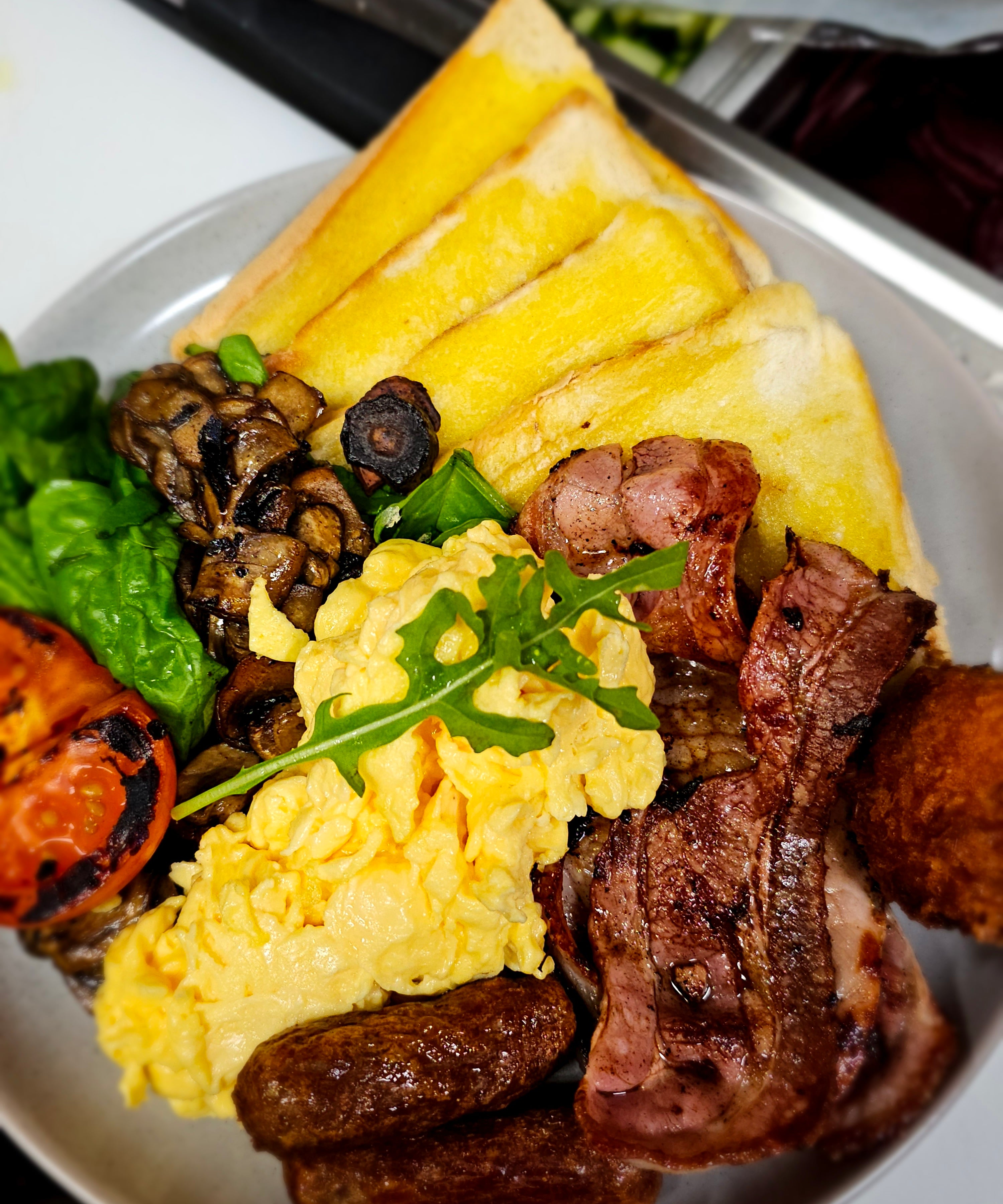 Bruce Almighty breakfast plate with bacon, eggs, chipolatas, hash brown, grilled mushrooms, spinach, grilled tomato, and toast at The Social Cafe in Emerald QLD 4720.
