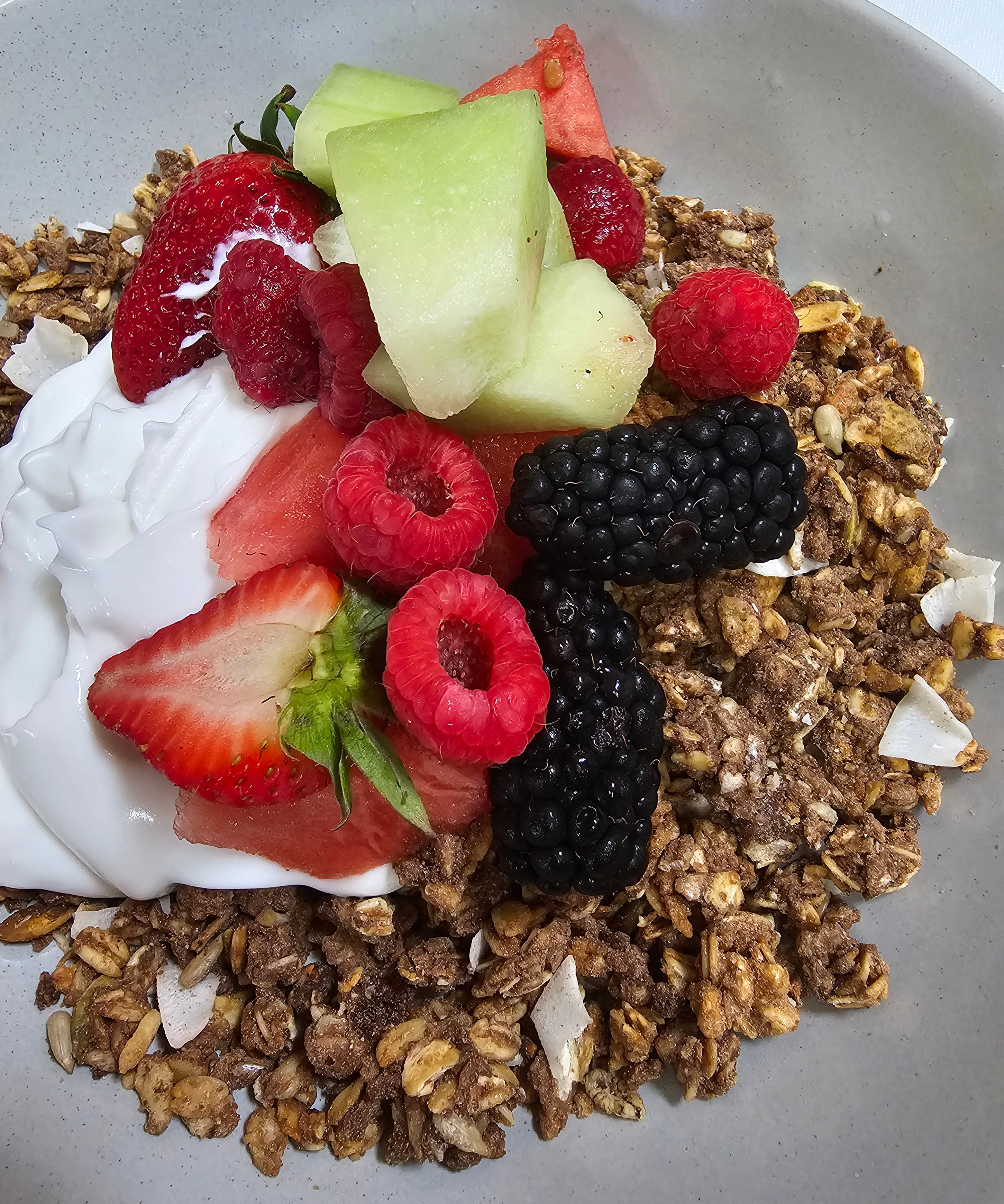 Wholesome granola with creamy coconut yogurt, fresh seasonal fruits, and berry coulis from The Social Cafe in Emerald QLD 4720.