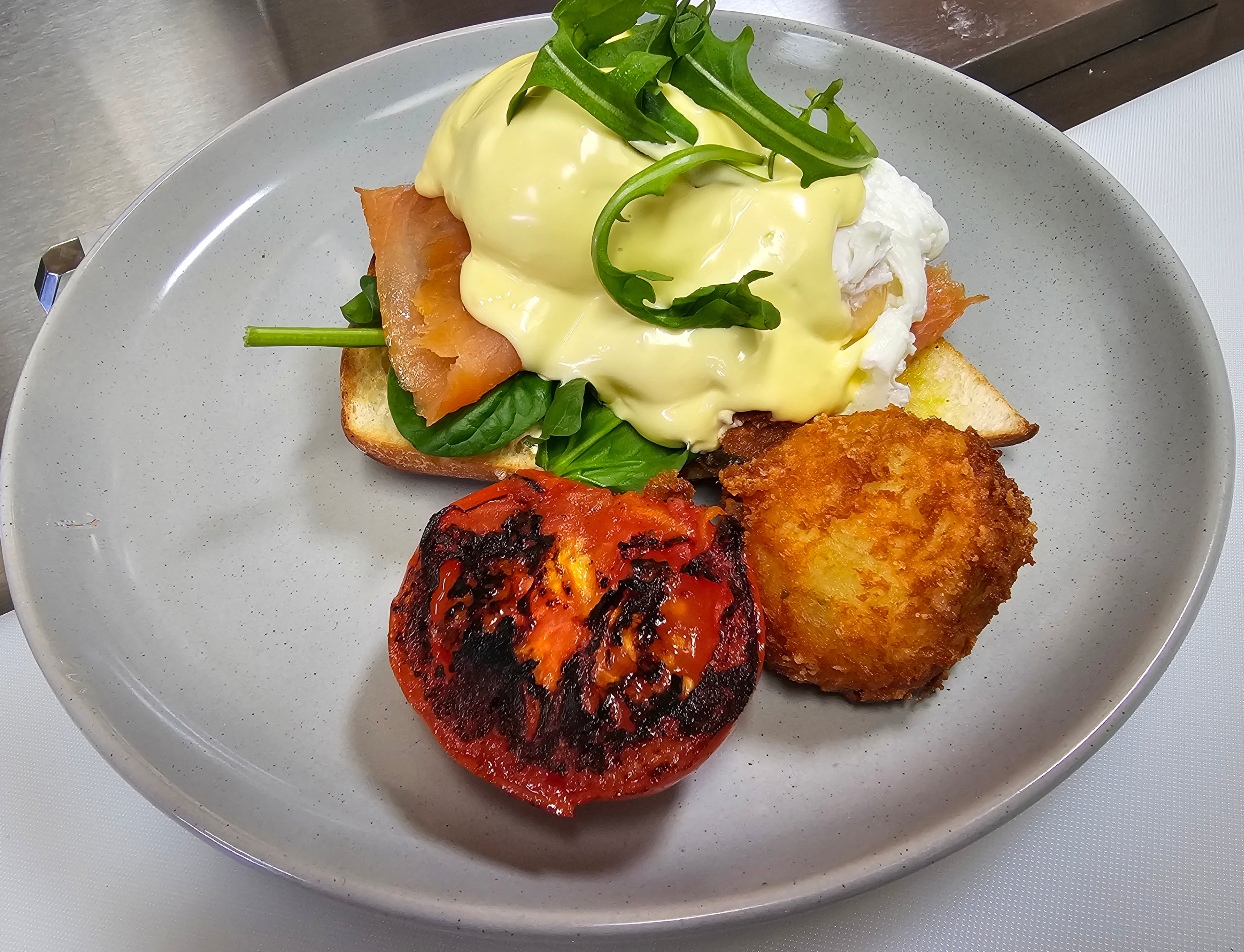 Terry Benedict with poached eggs, spinach, toasted Turkish bread, choice of bacon, ham, pulled pork, smoked salmon, or halloumi, grilled tomato, and homemade hash brown at The Social Cafe in Emerald QLD 4720.